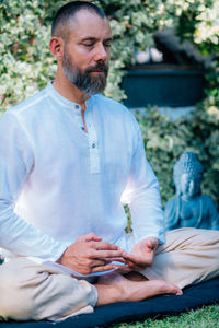 Meditating man. peaceful man sitting in a lotus position and meditating in the garden.