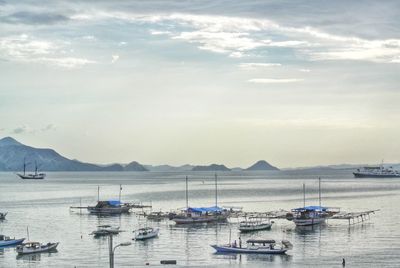 Boats in sea against cloudy sky