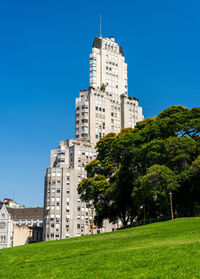 Buildings in field against clear blue sky