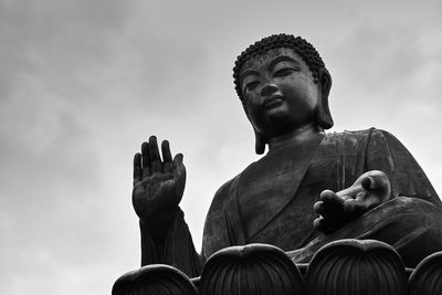 Low angle view of buddha statue against sky