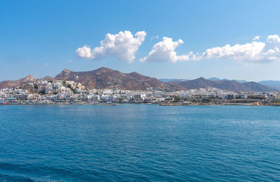 Scenic view of sea by townscape against sky