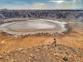 High angle view of mid adult man standing on arid landscape against sky