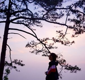 Rear view of silhouette woman standing by tree against sky