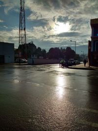 Surface level of wet street against sky in city