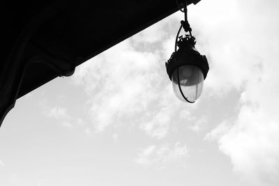 Low angle view of lighting equipment hanging against sky