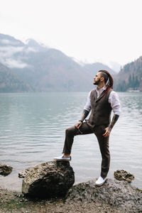 Full length of man standing on rock by lake