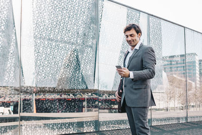 Businessman using mobile phone on bridge in city