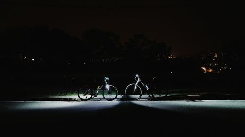 Silhouette bicycle against trees at night