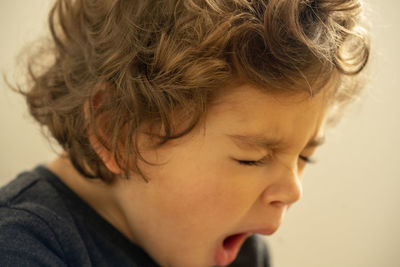 Close-up portrait of cute boy yawning