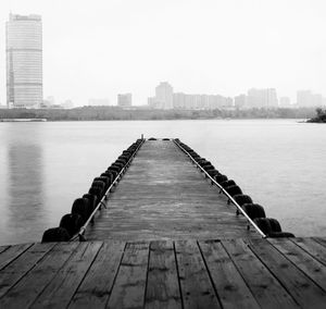 Pier over river in city against clear sky