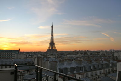 Eiffel tower amidst cityscape against sky during sunset