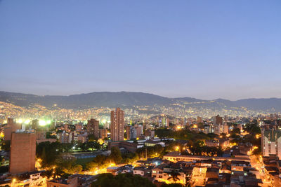 Illuminated cityscape against clear sky at night