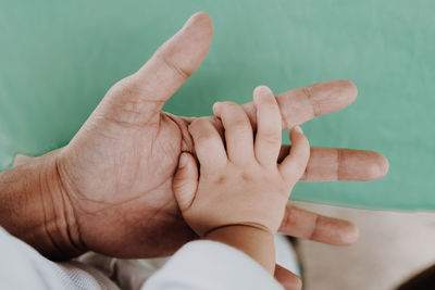 Cropped image of baby holding father hand