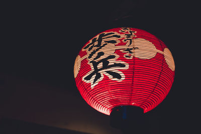 Low angle view of illuminated lantern hanging against black background