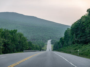 Road leading towards mountains against sky