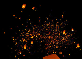 Low angle view of lanterns flying against sky at night