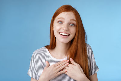 Smiling woman showing gratitude against blue background