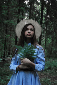 Portrait of woman wearing hat standing in forest