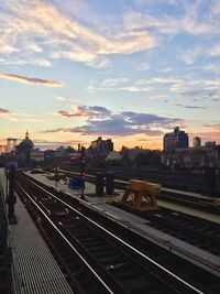 Railroad tracks in city against cloudy sky