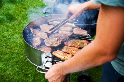 Midsection of man preparing food on barbecue grill