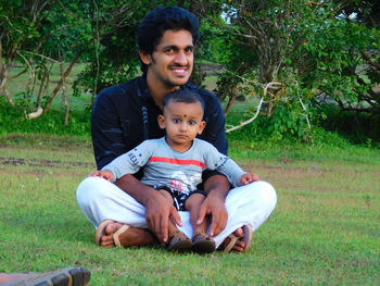Portrait of father and daughter sitting on grass