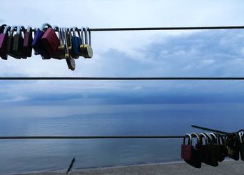 Clothes drying on clothesline by sea against sky