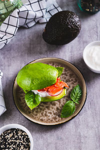 Avocado keto burger with red fish, radishes and sauce on a plate on the table vertical view