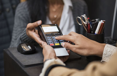 Woman doing credit card payment at checkout counter in store