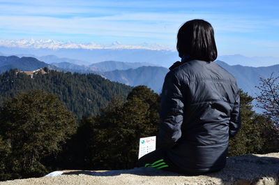 Rear view of man looking at mountains against sky