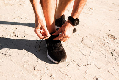 Low section of man relaxing on sand