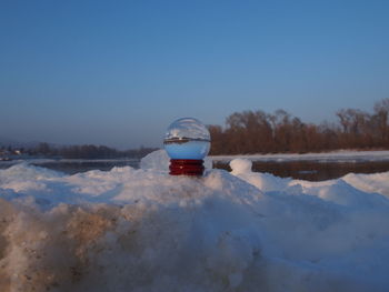 Car on snow covered landscape against clear blue sky