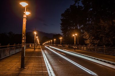 Illuminated light trails on road against sky at night