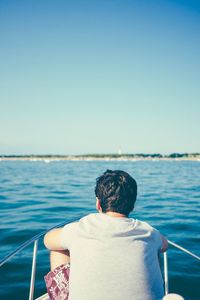 Rear view of man standing in sea against clear sky