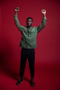 Portrait of young man standing against red background