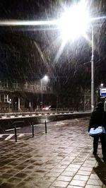 Illuminated people walking on snow covered road at night