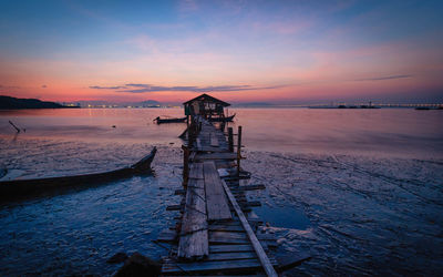 Pier over sea against sky during sunset