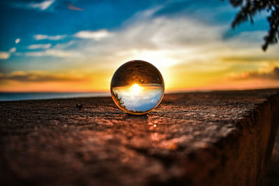 Close-up of crystal ball on beach against sky during sunset