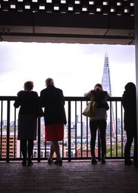 Rear view of silhouette people standing against railing