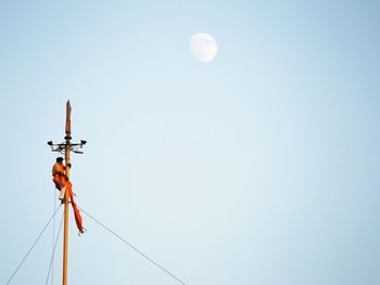 Low angle view of telephone pole against clear blue sky