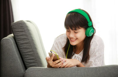 Young woman looking away while sitting on sofa