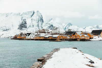 Traditional building by snowcapped mountain against sky