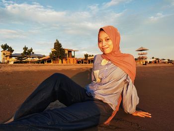 Young woman sitting against sky