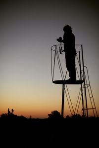 Silhouette man photographing on field against clear sky