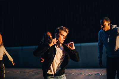 Young man dancing with friends at city in sunset