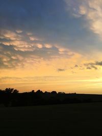 Scenic view of silhouette field against sky at sunset