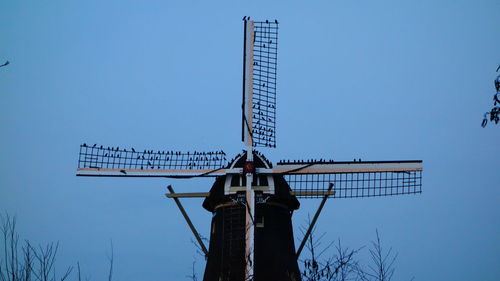 Low angle view of traditional windmill against clear blue sky