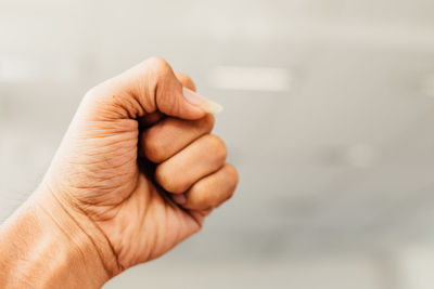 Cropped hand of man making fist against blurred background