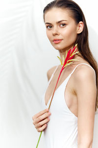 Portrait of smiling young woman standing against white background