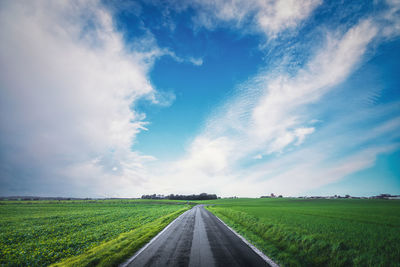 Road amidst field against sky