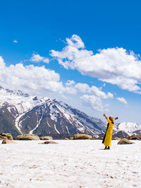 Rear view of woman standing on snowcapped mountain against sky